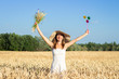 © Alex - Young beautiful woman in a white dress and hat holds a bouquet with wildflowers and a toy visor on a milf's field. Concept of outdoor recreation, a trip to the village
