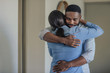 Affectionate young African American man hugging his wife at home