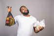 Zero waste concept. African american black men is holding mesh bag with products with no plastic package isolated over grey background with free space.