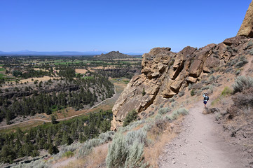 Wall Mural - Woman hikes and photographs Misery Ridge Trail in Smith Rock State Park near Terrebonne, Oregon on cloudless summer day.