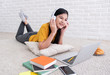 © weedezign - Asian female listen to music and use laptop computer to work at home.woman lay down on carpet at brick wall.working online lifestyle