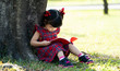 © Asada - Asian kid girl reading the book under the tree. Education and knowledge concept.