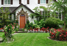 Stucco House With Wooden Front Door And Flowers In Front Yard