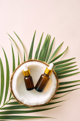 Wall Mural - coconut oil in bottle with open nuts and pulp in jar, green palm leaf background. natural cosmetic p