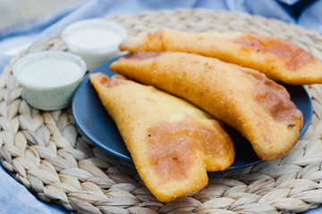 Wall Mural - Empanadas venezolanas on a rustic background with different sauces like guasacaca and spicy sauce. Empanada from Venezuela is fried and made with maize.