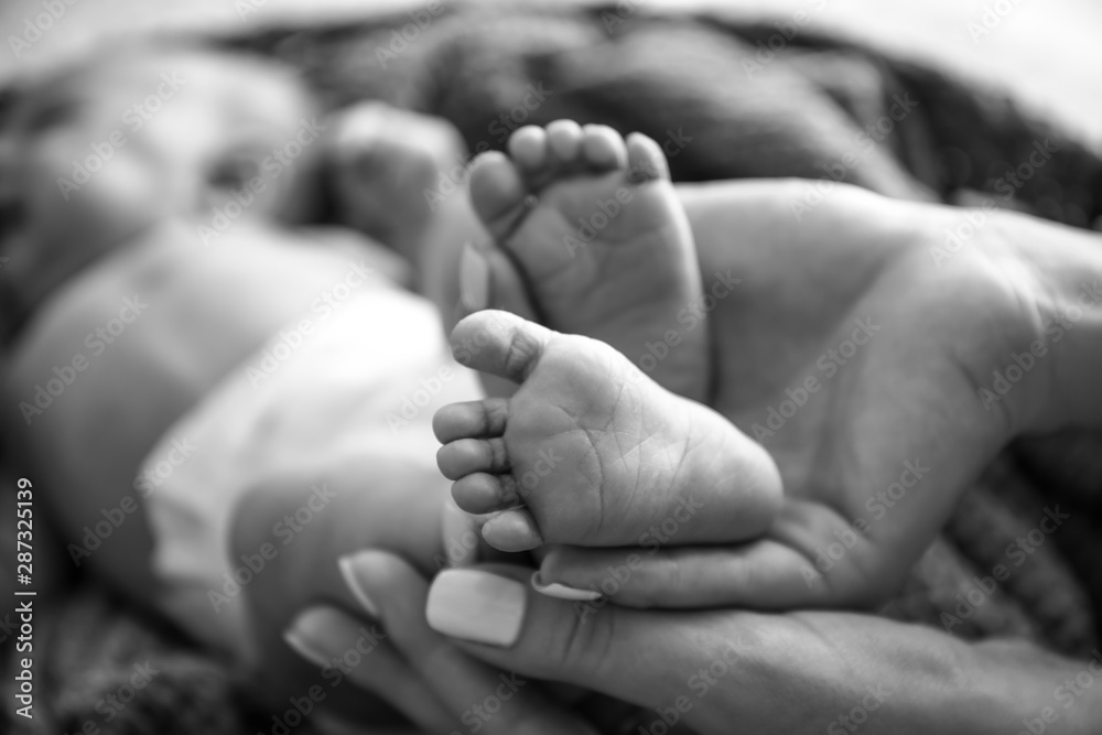 Mother's hands with tiny baby legs, closeup