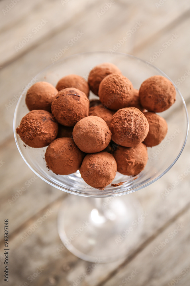Glass with tasty sweet truffles on table, closeup
