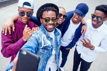 a group of five fashionable cool African American guys students communicating on the street looking at smartphone take pictures selfie on phone in street