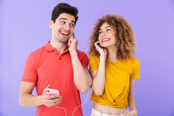 Poster - Portrait of smiling caucasian people man and woman listening to music together with cellphone and earphones