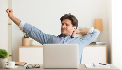 Poster - Young Man Stretching Hands Woking On Laptop At Home