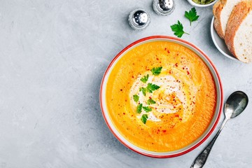 Canvas Print - Carrot and pumpkin cream soup with parsley on gray stone background.