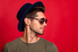 © deagreez - Profile photo of amazing guy wear vintage hat sun specs and grey t-shirt isolated on red background