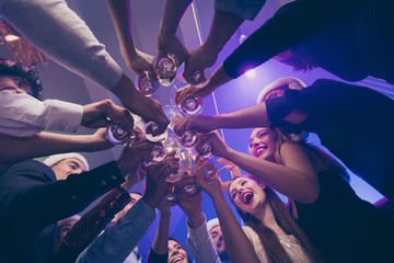 Low below angle view of nice attractive cheerful cheery girls and guys having fun rest relax clinking wineglass congrats corporate event feast celebratory in luxury place nightclub lights indoors