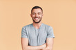 © GVS - Happy smiling handsome man with crossed arms looking to camera over beige background
