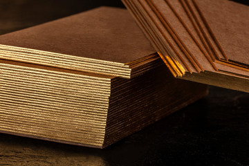 Wall Mural - A mockup for a stack of brown kraft business cards with gold painted edges on a black background, with a place for text