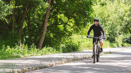 Wall Mural - Focused professional cyclist riding down park road