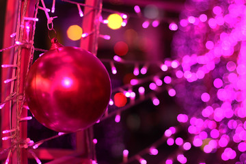 Red ball in Glamour Ultra Violet sparkling and purple glitter bokeh of metallic circle. Multicolored Christmas and New Year glowing light abstract for Christmas and holiday concept.