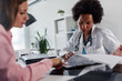 © lordn - Doctor talking with patient at desk in medical office. Health care concept, medical insurance. Womens health.