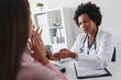 © lordn - A female doctor sits at her desk and talks to a female patient while looking at her mamogram. Brest cancer