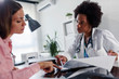 © lordn - Doctor talking with patient at desk in medical office. Health care concept, medical insurance. Womens health.