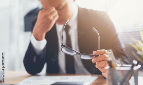 Fotomural Businessman in black suit of hands touching on the eyes due to tiredness from working computer for a long time, may be the cause of office syndrome