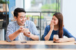 © chayathon2000 - Asian couple in blue shirt drinking coffee talking and working with computer laptop smile and  happy mood in coffee shop cafe