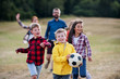 © Halfpoint - Group of school children with teacher on field trip in nature, playing with a ball.