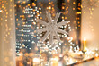 christmas and holidays concept - paper snowflake decoration hanging over garland lights and candles at night window