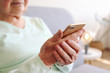 © Evrymmnt - Elderly woman holding blank screen cell phone gadget in hands. Old lady with wrinkled skin trying to vigure out touchscreen smartphone. Background, close up, overhead, top view, copy space.