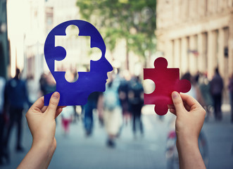 Two hands holding a paper with human head and a puzzle piece. Finding a cure to heal the disease. Mental health concept, memory loss and dementia disease. Alzheimer's losing brain and memory function.