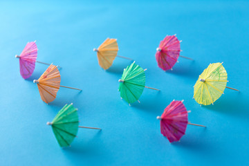 Wall Mural - summer, accessory and decoration concept - cocktail umbrellas on blue background