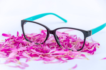 clise up of eyeglasses with petal of purple flowers isolated on white background.