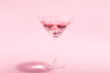 Sticker - Cocktail in glass with eyelashes on pink background. Minimalism concept