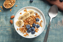 Bowl Of Yogurt With Blueberries, Banana And Oatmeal On Color Wooden Table, Flat Lay