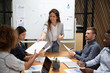 © fizkes - Smiling female leader give paper report to employees at meeting