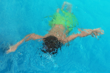 Poster - Little child under water in outdoor swimming pool. Dangerous situation