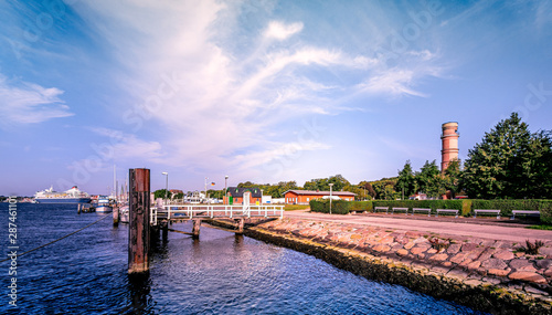 Fotografia  lübeck travemünde with old lighthouse and cruise ship in the background early in