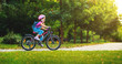© JenkoAtaman - happy cheerful child girl riding a bike in Park in nature.