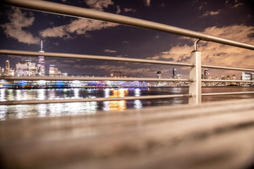 Fototapete - New York City skyline toward Lower Manhattan seen that night through railings along the pier