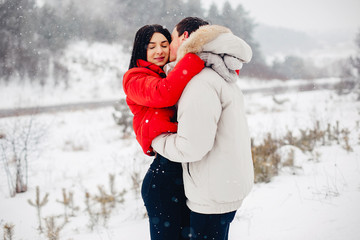 Wall Mural - Young couple in a winter park. Man with a red sharf. Lady in a red jacket