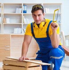 Repairman carpenter working sawing a wooden board with a hand sa