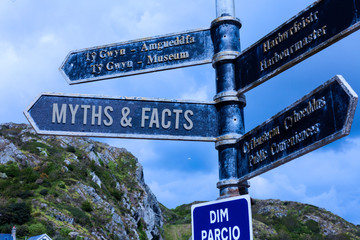 Word writing text Myths And Facts. Business photo showcasing usually traditional story of ostensibly historical events Road sign on the crossroads with blue cloudy sky in the background