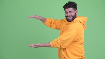 Wall Mural - Funny young overweight bearded Indian man snapping fingers and looking guilty