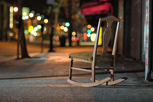 A Rocking Chair On A City Sidewalk,