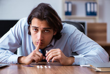 Young Man Having Problems With Narcotics At Workplace