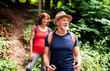 © Halfpoint - Senior tourist couple with backpacks on a walk in forest in nature.