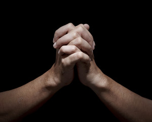 Man hands in praying position low key image. High Contrast isolated  on Black Background.