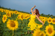 © Михаил Решетников - A red-haired woman in a yellow dress is standing in a field of sunflowers. Beautiful girl in a skirt sun enjoys a cloudless day in the countryside. Pink locks of hair.