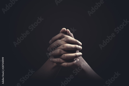 Fotomural Praying hands with faith in religion and belief in God on dark background