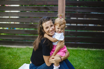 Wall Mural - Happy mother and daughter together on green grass.